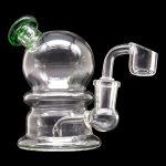 Clear glass dab rig with green accents and a quartz banger.