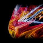 Vibrant glass pipe with swirling red, orange, and yellow patterns against a black background.