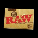 A close-up, angled shot of the RAW Classic 1 1/2" Rolling Papers package against a dark background, highlighting the brand lettering.