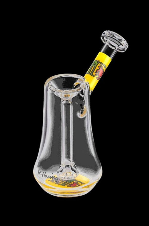 A three-quarter view of the K. Haring Glass Bubbler, showcasing the clear glass construction and colorful artwork.