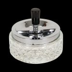 A close-up, angled view of the Glass Spinning Ashtray, showcasing its clear glass construction and circular design.