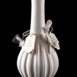 Elegant white glass water pipe with a textured bulbous base and decorative tag, reflected on a dark surface.