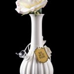 Elegant white glass vase with a cannabis bud displayed inside, tagged “My Bud Vase” and reflecting on a black surface.