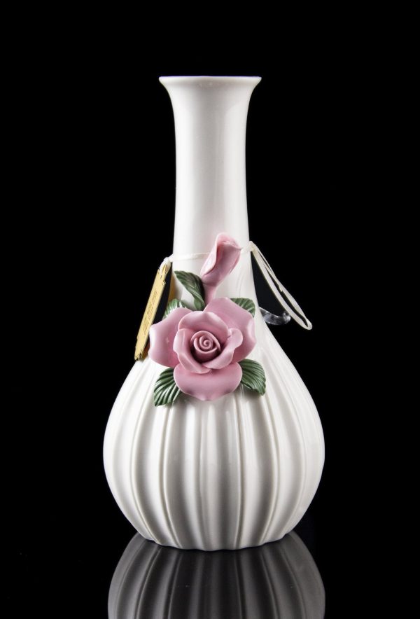 White ceramic bubbler with delicate pink rose embellishment, reflecting on a dark surface.