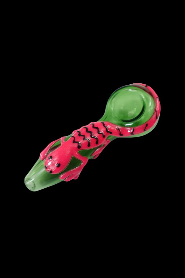 Green and pink glass pipe shaped like a scorpion, isolated on a black background.