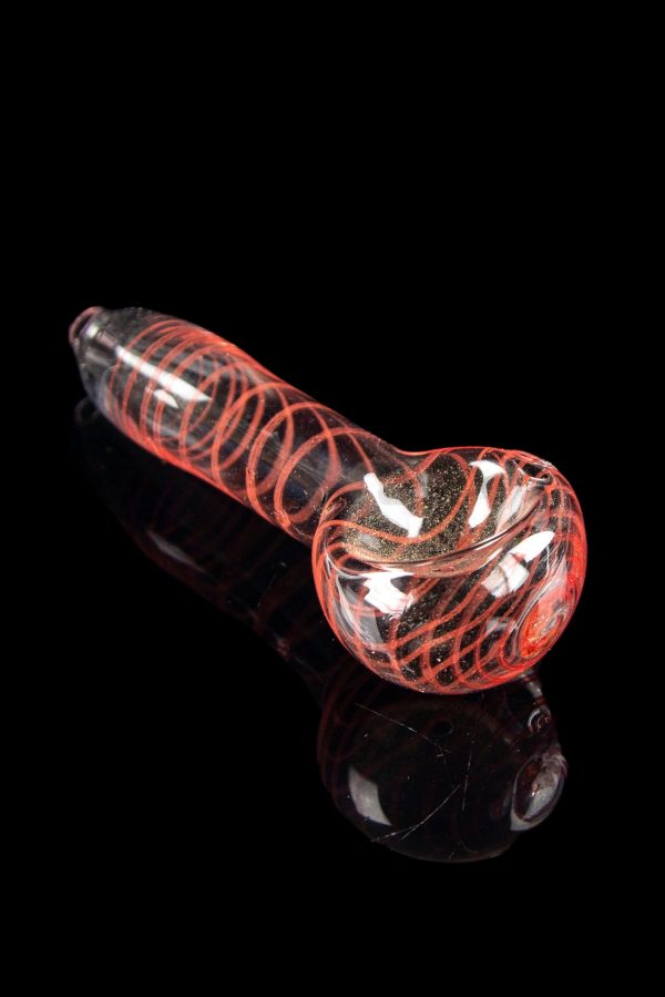 Glass pipe with red and white swirling patterns, reflecting on a dark surface.