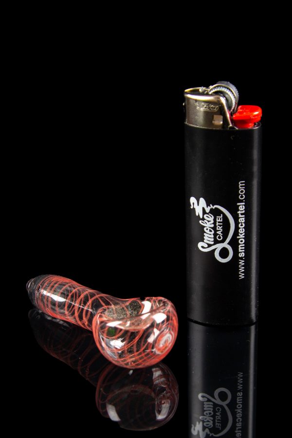 Red glass bubbler pipe and black lighter with "Smoke Cartel" branding on a reflective surface.