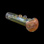 Glass pipe with red and orange speckled bowl, isolated on black.