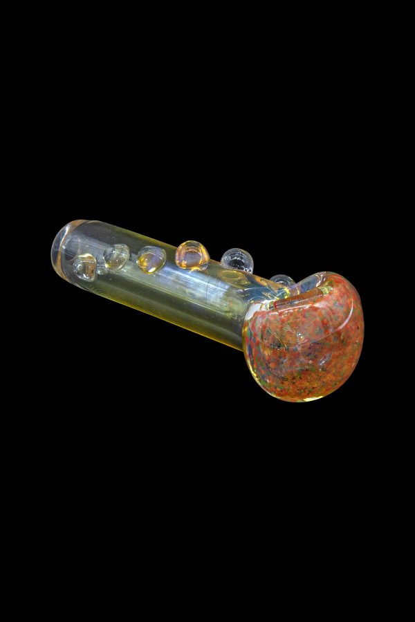 Glass pipe with red and orange speckled bowl, isolated on black.