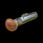 Glass pipe with red and orange speckled bowl against a black background.
