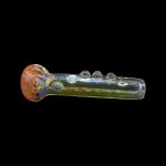 Hand-blown glass pipe with vibrant red and gold accents, isolated on a black background.