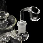 Clear glass dab rig with a quartz banger against a black background.