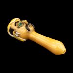 Hand-blown glass pipe with a skull design, isolated on a black background.