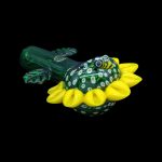 Hand-blown glass cannabis rig shaped like a frog with yellow floral accents, isolated on a black background.