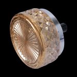 Golden glass cannabis grinder with metallic base, isolated on black.