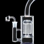 Clear glass water pipe (rig) with a perc filtration system and dab nail, isolated on black.