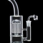 Clear glass water pipe (rig) with a perc filtration system and a quartz nail for dabbing cannabis concentrates.