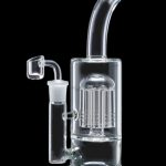 Clear glass dab rig with multiple diffusion perc chambers, featuring a quartz banger and accompanying glass attachment, isolated on a black background.