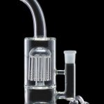Clear glass water pipe (bong) with percolator and teal accents, isolated on a black background.