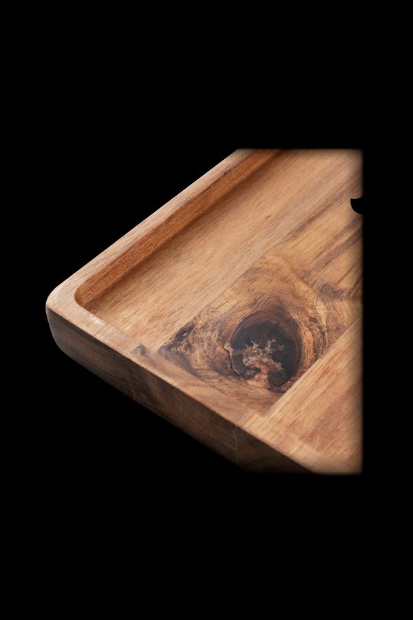 Wooden rolling tray with a natural knot detail, angled on a black background.
