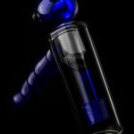 Blue glass oil rig with intricate curves against a black background.