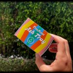 Hand holding a pink “Treehouse Ash Tray” against a blurred green foliage background.