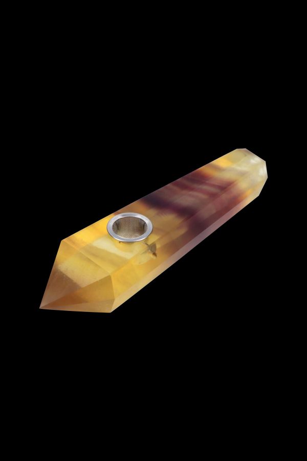 A golden-brown crystal pipe with a metal bowl, isolated on a black background.