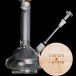 Glass water pipe (bong) with wooden base displaying “Canada Puffin” logo.