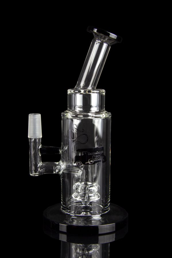 Clear glass water pipe (rig) with intricate bubbler design, reflecting on a glossy black surface.