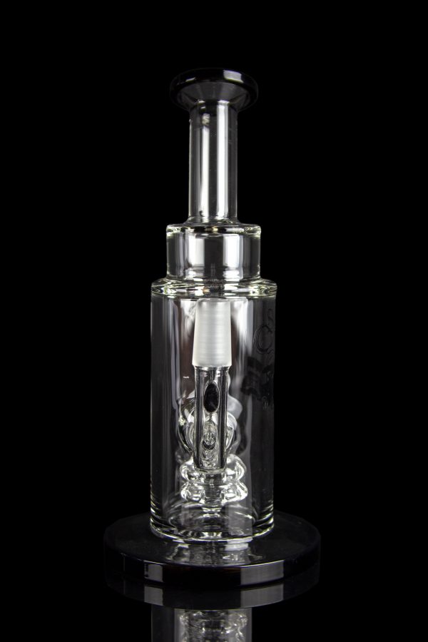 Clear glass oil rig with intricate bubbler design, displayed on a reflective surface against a black background.