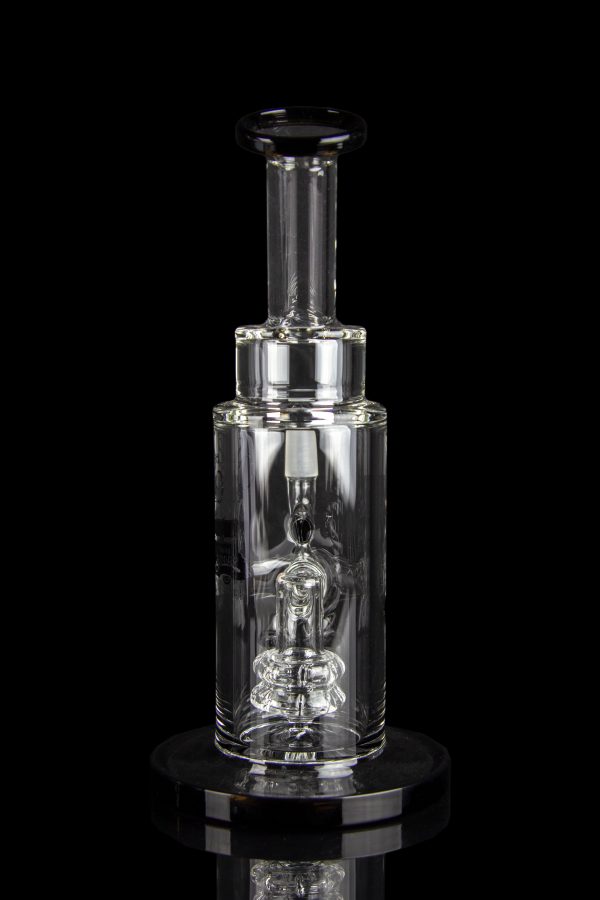 Clear glass dab rig with intricate percolator and vapor pathway, displayed on a reflective surface.