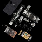 A collection of glass cannabis smoking accessories including a bubbler, various adapters, a silicone case, a cleaning brush, and a small package of cleaning solution, all displayed on a black background.",