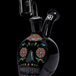 Black glass skull rig with colorful floral Day of the Dead-inspired design, featuring a downstem and mouthpiece.