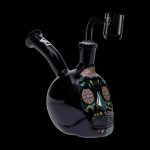 Black glass water pipe shaped like a sugar skull with colorful floral details, accompanied by a glass downstem.