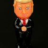 A glossy, cartoonish figurine of Donald Trump in a suit, likely a novelty item related to cannabis accessories.