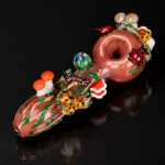 Hand-blown glass pipe adorned with colorful mushroom designs, studio shot on a black reflective surface.