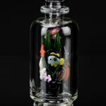 Clear glass bubbler with colorful sculpted glass flowers and foliage inside, reflecting on a glossy black surface.