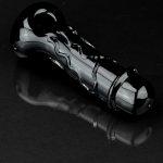 Black glass cannabis pipe with swirling design, reflecting on a dark surface.