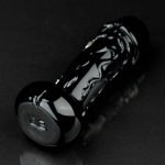 Black glass pipe with intricate white swirls, resting on a reflective surface.