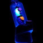 Glowing electric dab rig with cannabis concentrate visible inside, set against a black background.