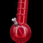 Red glass water pipe (bong) against a black background.