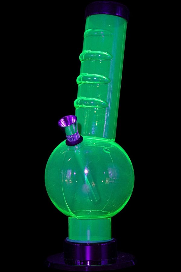 Glowing green glass water pipe (bong) with purple accents on a black background.