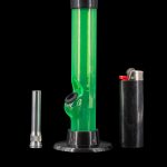 Green glass bong with a metal bowl and lighter on a black background.