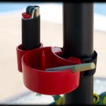 Red ashtray and lighter holder clipped to a black pole, likely for cannabis use.