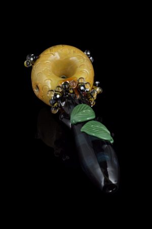 A detailed side view of the Empire Glassworks Spoon Pipe - Honey Pot, showcasing its honey-colored glass and detailed sculpted design.
