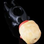 Black glass water pipe with a peach-colored mouthpiece resting on a black surface.