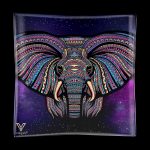 A vibrant, patterned elephant head design on a glass tray with a starry purple background, branded with a cannabis accessory company logo.