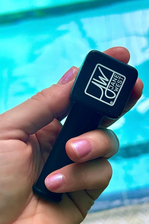 Hand holding a black Jane West cannabis accessory, likely a pipe or one-hitter, with branded logo.