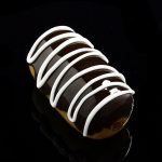 A close-up, angled view of the Glassheads "Sweet Eclair" Chillum, resembling a glazed pastry with its swirled glass design.