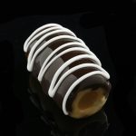 A close-up, angled view of the Glassheads “Sweet Eclair” Chillum, featuring a layered, creamy white design on a dark background.